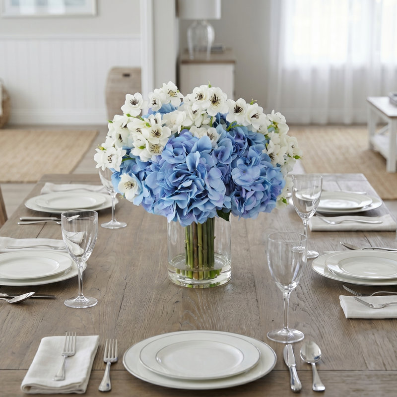 Arrangement d'hortensias et de fleurs de cerisier dans un vase en verre