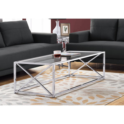 Table basse spacieuse avec plateau en verre transparent et base en métal poli