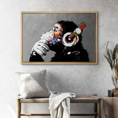 Wall art of a chimpanzee wearing vibrant, multicolored headphones in a landscape-oriented wood frame.