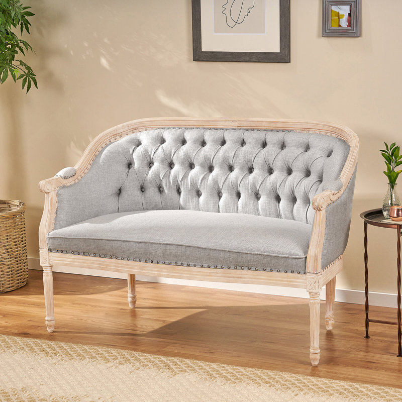 Élégante causeuse capitonnée de style Chesterfield avec structure en bois de bouleau et garnitures cloutées, parfaite pour les intérieurs classiques et contemporains.
