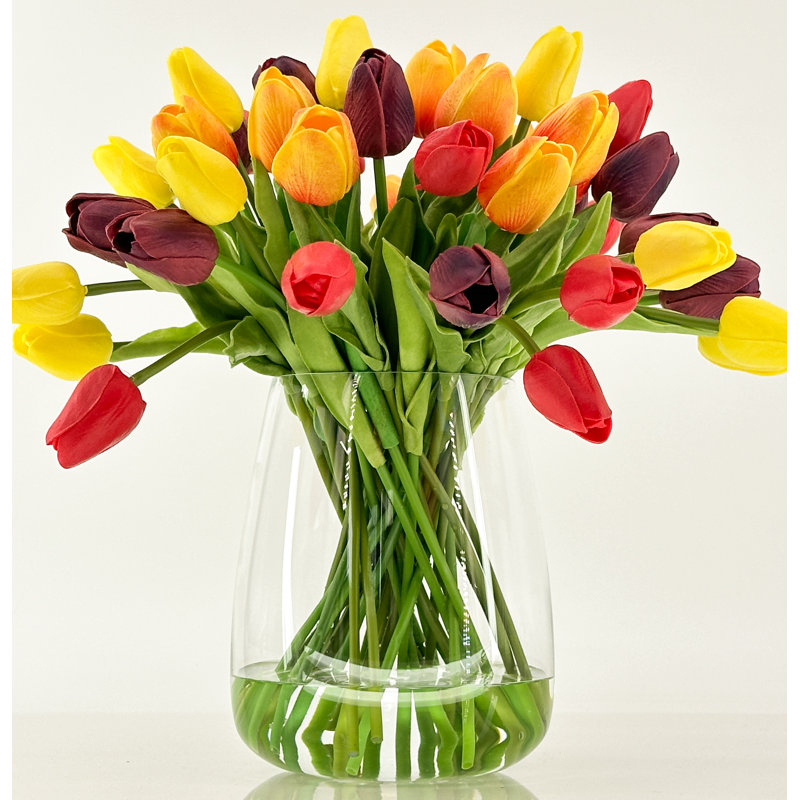 Vraies tulipes dans un vase en verre, fleurs artificielles oranges