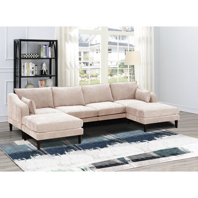 Ensemble de salon modulable 6 pièces, en suède rose poudré, comprenant fauteuils, coussins, canapé et pieds en bois.