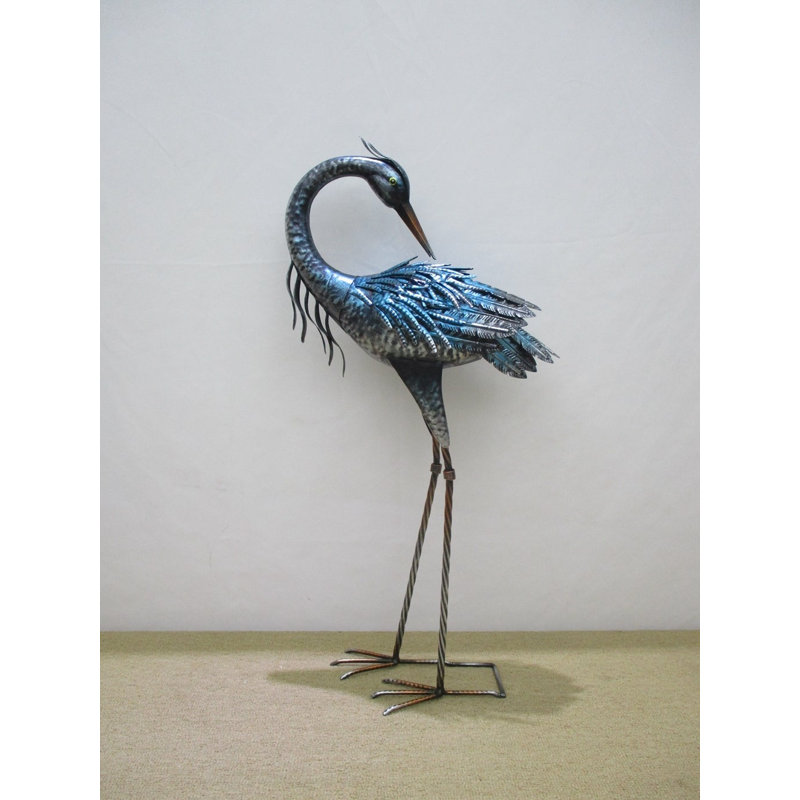 Sculpture grue bleue derrière un jardin