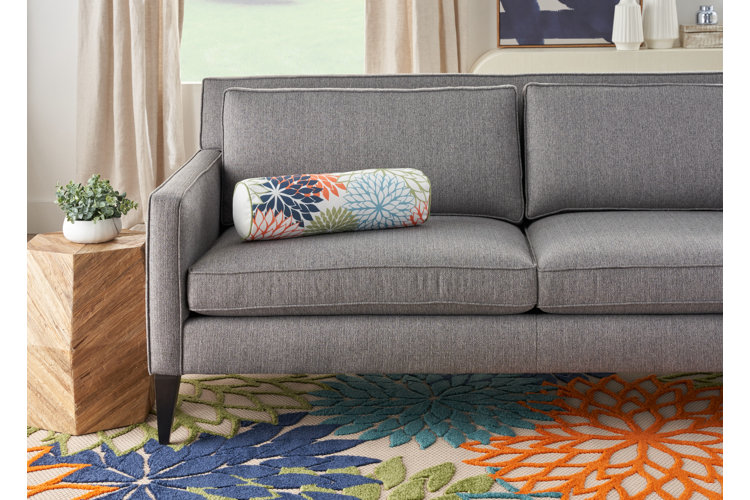 multicolor floral print bolster pillow on a gray loveseat