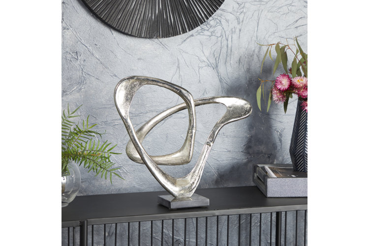 Silver aluminum metal sculpture on a table beside flowers.