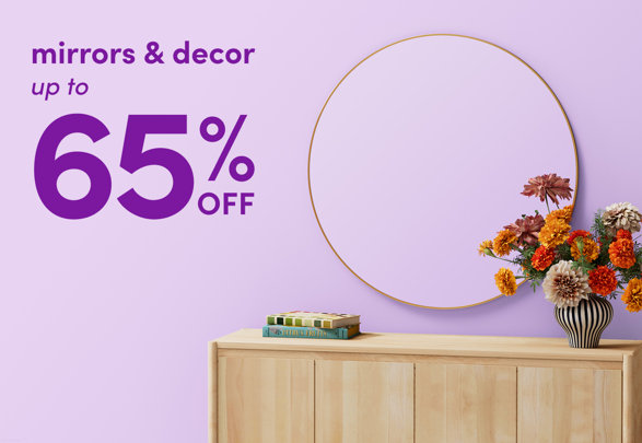 Mirrors and decor up to 65% off featuring a round gold-rimmed mirror hanging over a light wood console table with books and a floral arrangement.