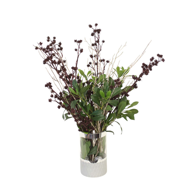 Tiges de couronne pailletées brunes mélangées à de la verdure dans un vase en verre