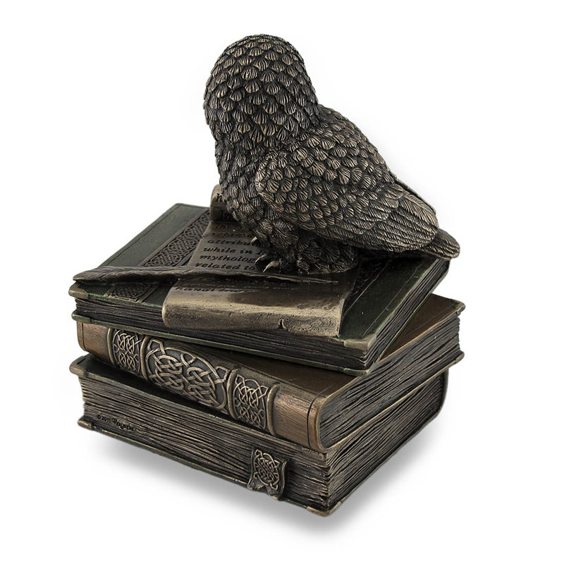 Statue de hibou perché sur une pile de livres