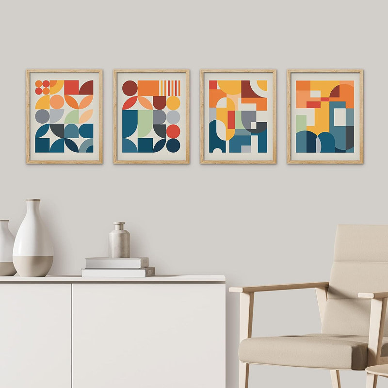 Set of four framed wall art prints featuring colorful mid-century modern geometric shapes in natural wood frames.