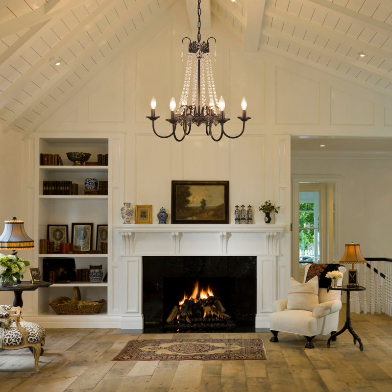 Crystal-draped chandelier hanging in a bright, traditional living room with vaulted ceilings, fireplace, and vintage furnishings.