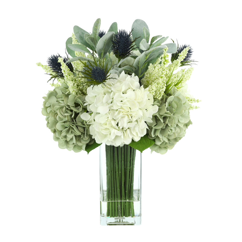 Hortensias Maegan assortis, oreille d'agneau et protea disposés dans un vase en verre
