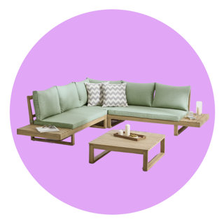 L-shaped outdoor wooden corner sofa with sage green cushions, chevron accent pillows, and a matching coffee table on a lavender circular background.