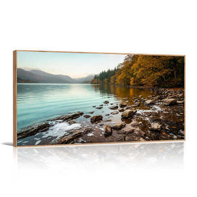 Tableau sur toile représentant un lac bleu avec des montagnes au loin et des arbres dorés d'automne