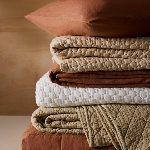 Stack of folded earth-toned bedding.
