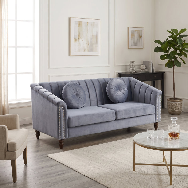 Canapé bleu clair capitonné, accoudoirs arrondis et finitions cloutées., Sofa