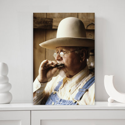 1960S Senior Man Wearing Wide Brim Hat Wire Rim Glasses Faded Blue Jean Bib Overhauls Sitting Playing Harmonica Classic Retro Vintage Portrait Wall...