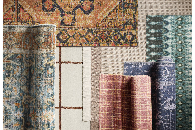 A collection of textured and patterned rugs including a cream grid rug with fringe, a rust traditional rug, and deep blue-grey options