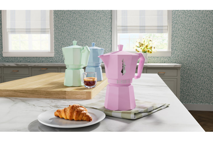 pastel color moka pots and a croissant on a kitchen counter