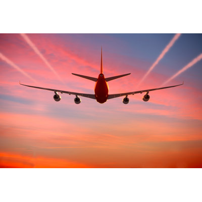 Airplane Flying in The Sky at Sunset with Vapor Trails by Maxiphoto