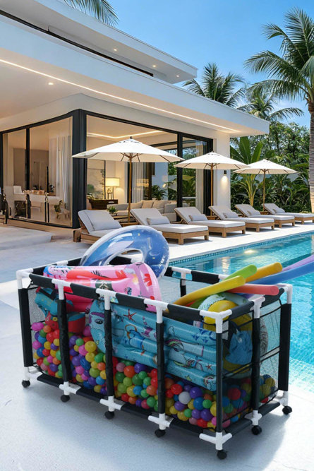 Bac de rangement roulant rempli de balles en plastique colorées, de flotteurs de piscine et de nouilles, sur un patio à côté d'une piscine avec des chaises longues et des parasols.