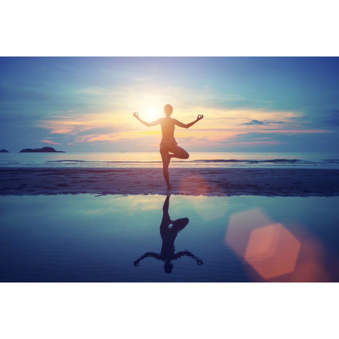 Leinwandbild Junge Yoga Frau Meditation am Strand bei Sonnenuntergang