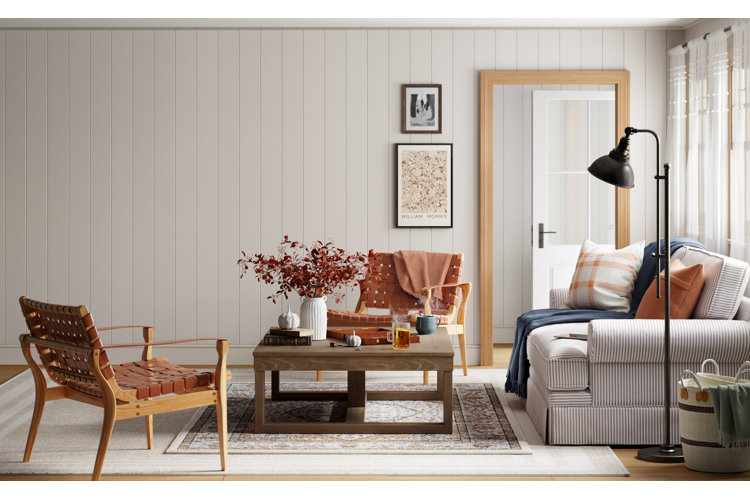 Living room with white wall paneling, baseboards, and a wood door frame next to a striped sofa and woven leather chairs.