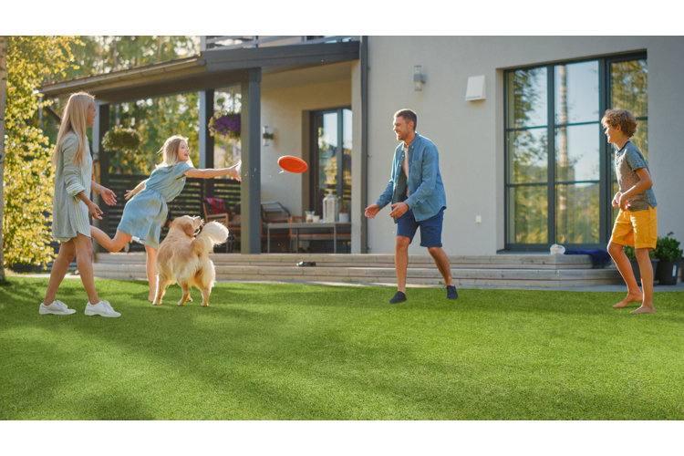 image of a happy family playing with a frisbee on the back lawn