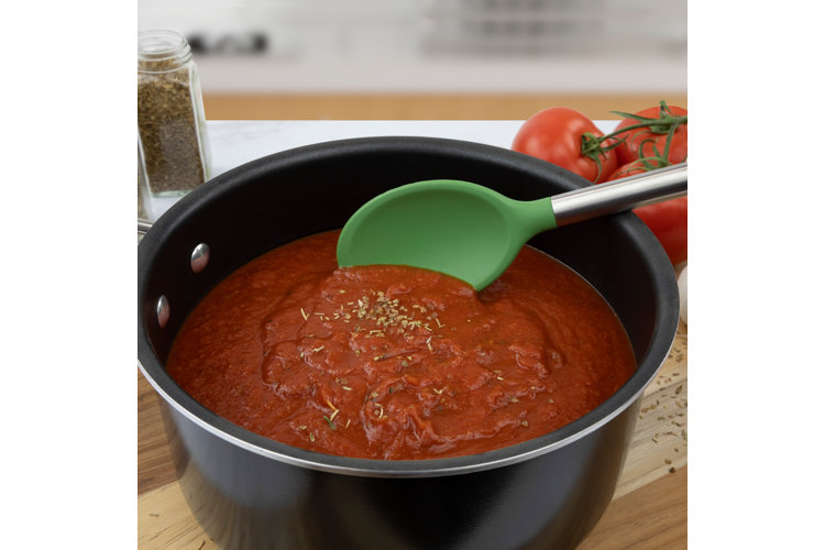 green mixing spoon in spaghetti sauce