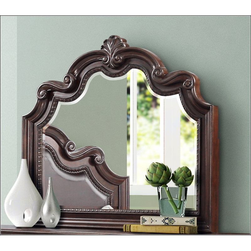Exquis miroir orné d'acajou avec des détails complexes et du verre biseauté, un ajout intemporel à tout décor intérieur.