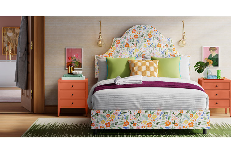 Eclectic bedroom with a floral upholstered bed green gray and purple bedspread and bright orange nightstands