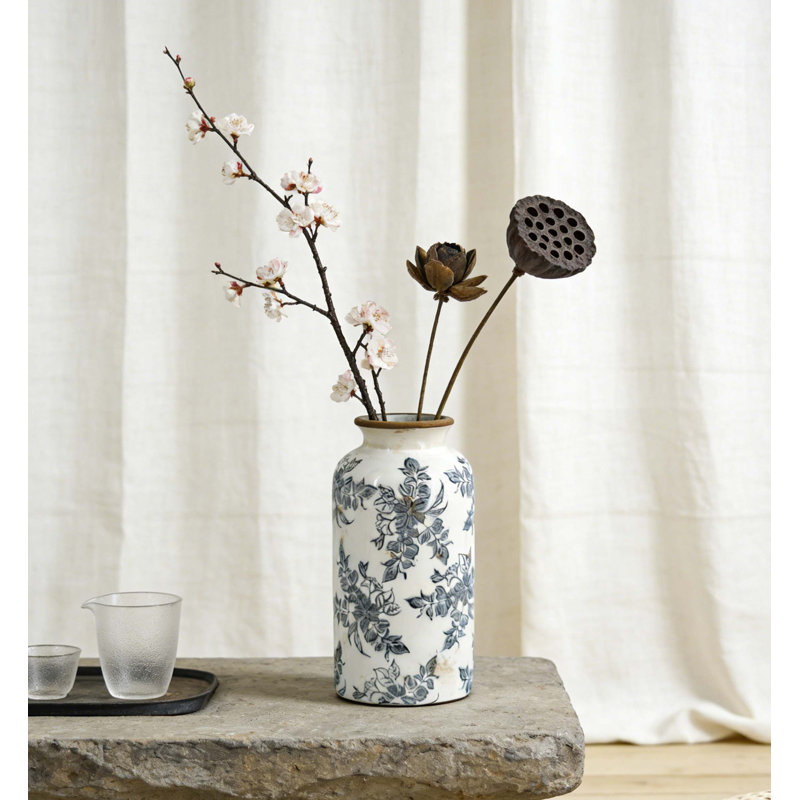Vase cylindrique en céramique avec motif floral d'inspiration rétro, finition blanc vieilli et fonctionnalité de présentation intemporelle.