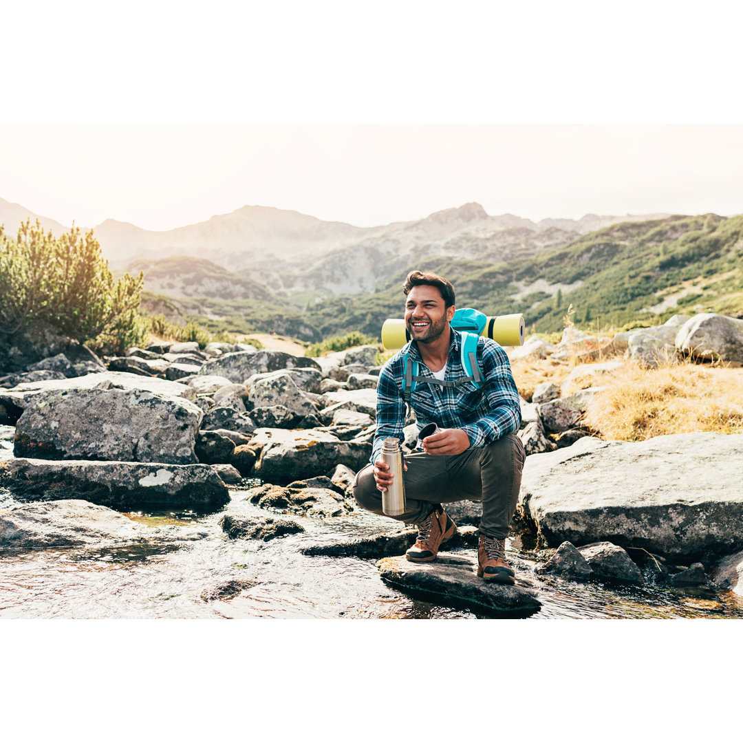 Happy Hiker By A Mountain Stream von Pixelfit - Kunstdrucke auf Leinwand ohne Rahmen