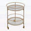 Chariot-bar rond avec tablettes en verre trempé et accents dorés, finition blanche vieillie, idéal pour les décors modernes et rétro