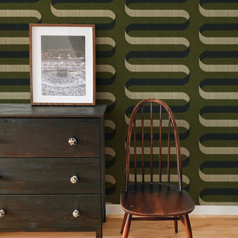 Olive wallpaper with dark wood dresser and chair.