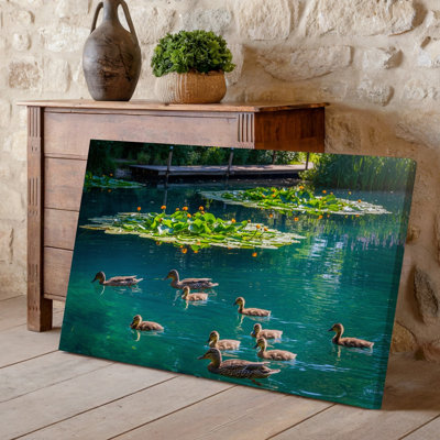 Canvas A Serene Pond Scene Featuring A Group Of Ducks Swimming Wall Art Peacefully In Clear Emerald Green Water Surrounded By Vibrant Canvas Wall Art