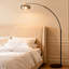 La lampe sur pied avec abat-jour en verre ambré avec un mât arqué au design moderne et minimaliste ajoute une atmosphère chaleureuse à l'espace.