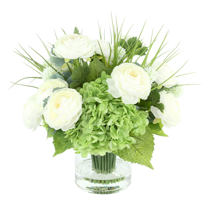 Renoncule, hortensia et herbe disposés dans un vase en verre