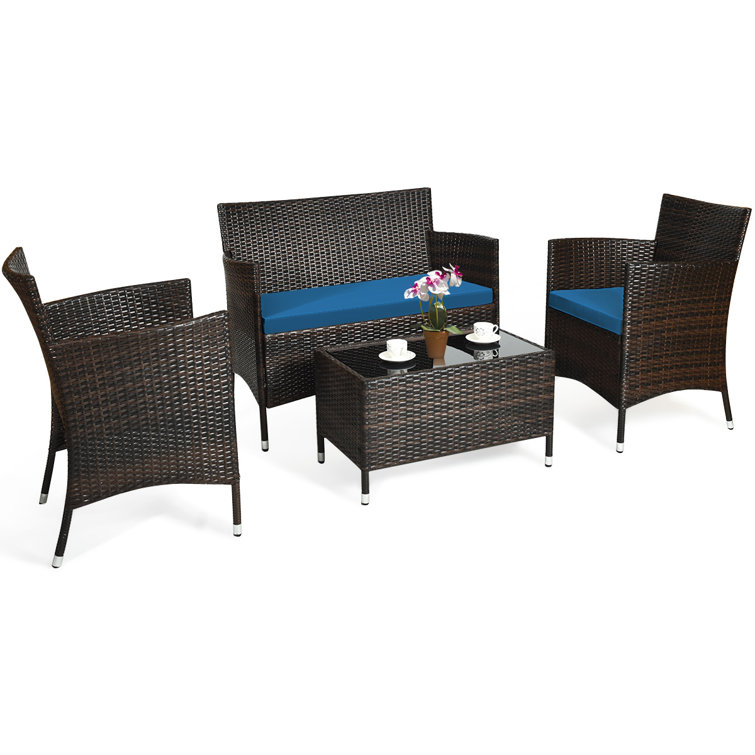 A brown and black outdoor seating set with a couch, two chairs, and a table