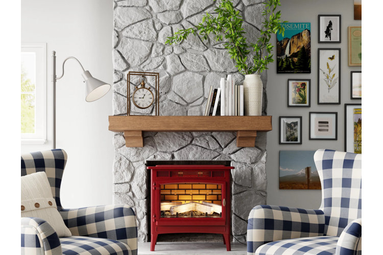 A pair of blue gingham armchairs on either side of a red electric fireplace stove that rests against a faux stone accent wall.