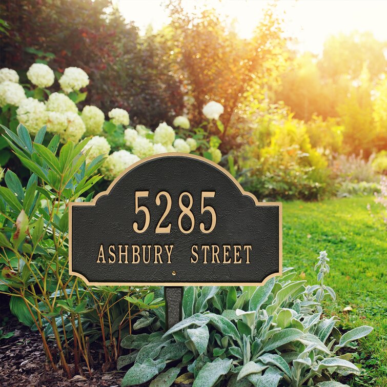 A black and gold address plaque in some bushes