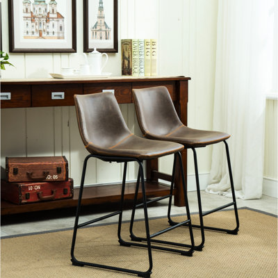 2 tabourets à hauteur de comptoir en brun antique. Sièges en plastique moulé recouverts de cuir rétro. Structure en fer noir. Dimensions: l 18,5 po x P 21,5 po, H 34,5 po. Siège: P 15,5 po, tabourets bruns, 2 po.