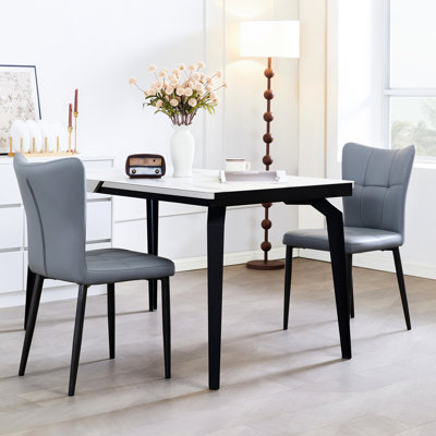 Paire de chaises de salle à manger ergonomiques à haut dossier avec support en fer forgé, revêtement en cuir et rembourrage confortable, idéal pour les espaces résidentiels de petite à moyenne taille.