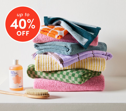 Bathroom essentials up to 40% off featuring colorful stacked towels with body wash and brush