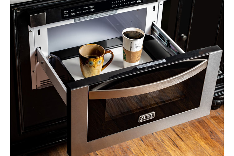 closeup of an open microwave drawer with a tall mug and starbucks cup inside