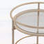 Chariot-bar rond avec tablettes en verre trempé et accents dorés, finition blanche vieillie, idéal pour les décors modernes et rétro