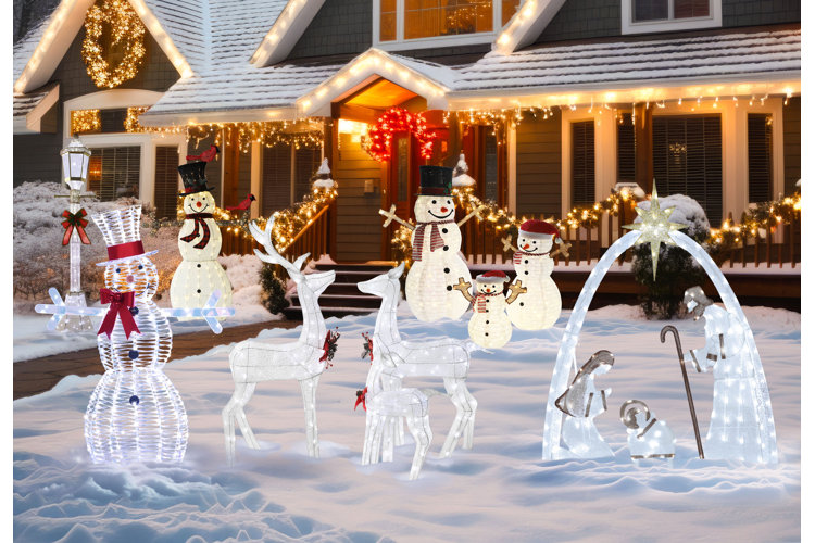 snowy front yard with lighted Christmas decor including a street lamp, snowmen, and reindeer