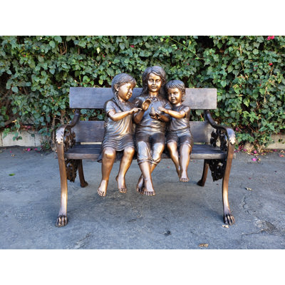 Trois enfants sur un banc tenant une statue d'oiseau