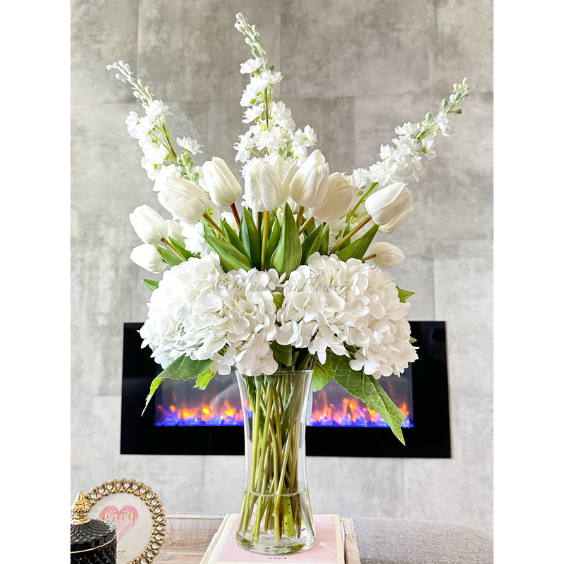 Pièce maîtresse artificielle, hydrangées et delphiniums dans un vase en verre
