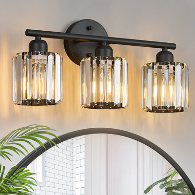 Applique murale verticale Kyneisha Modern Sand Black à 3 lumières en cristal, à placer au-dessus du miroir de la coiffeuse ou du lavabo. Compatible avec les ampoules à intensité variable (ampoules non comprises).