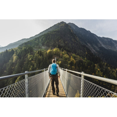 Randonneur solitaire marchant sur un pont suspendu entre deux montagnes de Deimagine